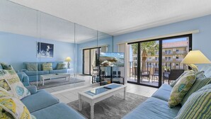 A modern living room with a blue sofa set, a coffee table, and a flat-screen TV.
