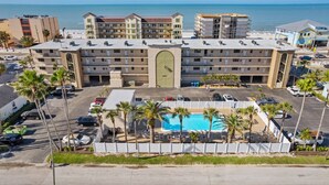 A hotel with a pool, multiple floors, and a view of the ocean.