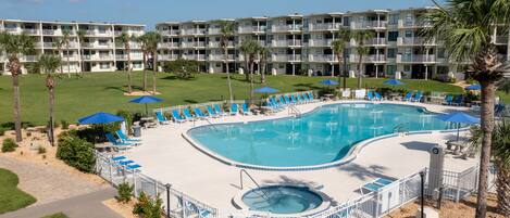 A hotel with a large pool area, multiple balconies, and a well-maintained lawn.