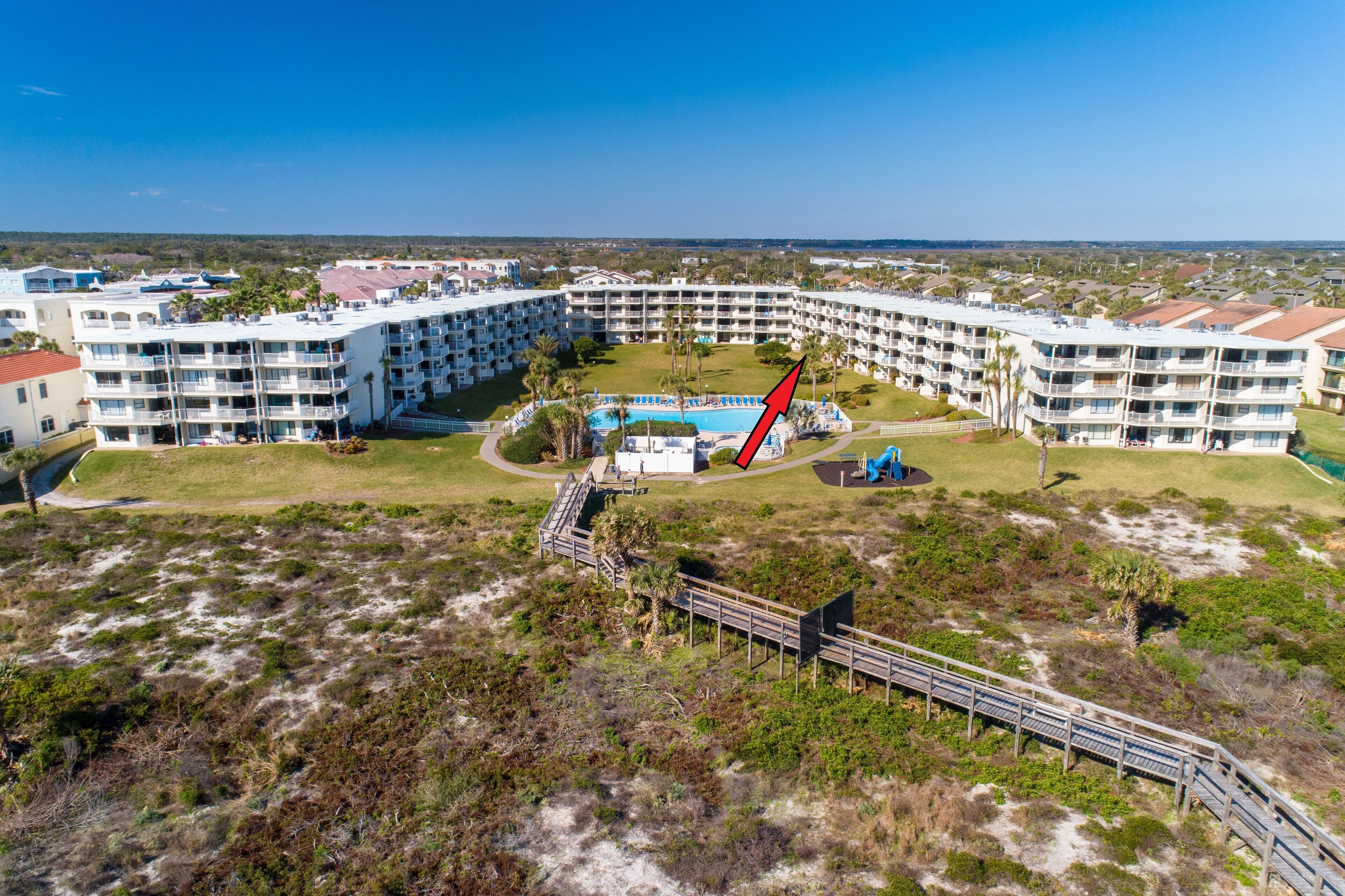 Et stort resort med flere altaner, en central pool og et græsslået område omkring.