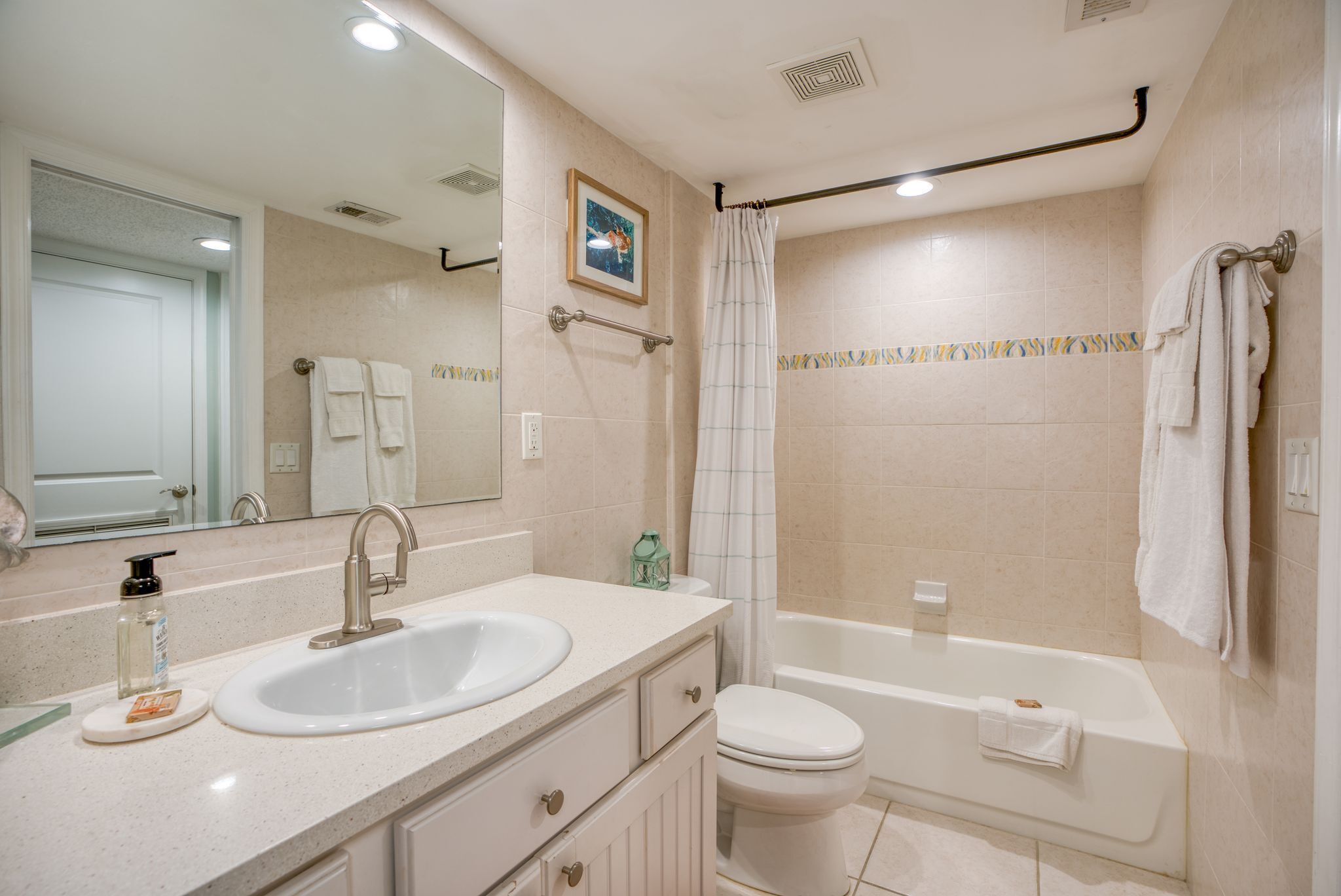 A bathroom with a sink, mirror, toilet, and bathtub.