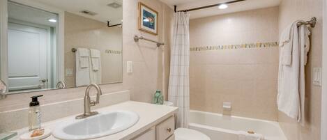 A bathroom with a sink, mirror, toilet, and bathtub.