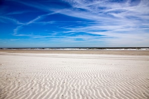 Ein Strand mit Sandstrukturen und blauem Himmel.
