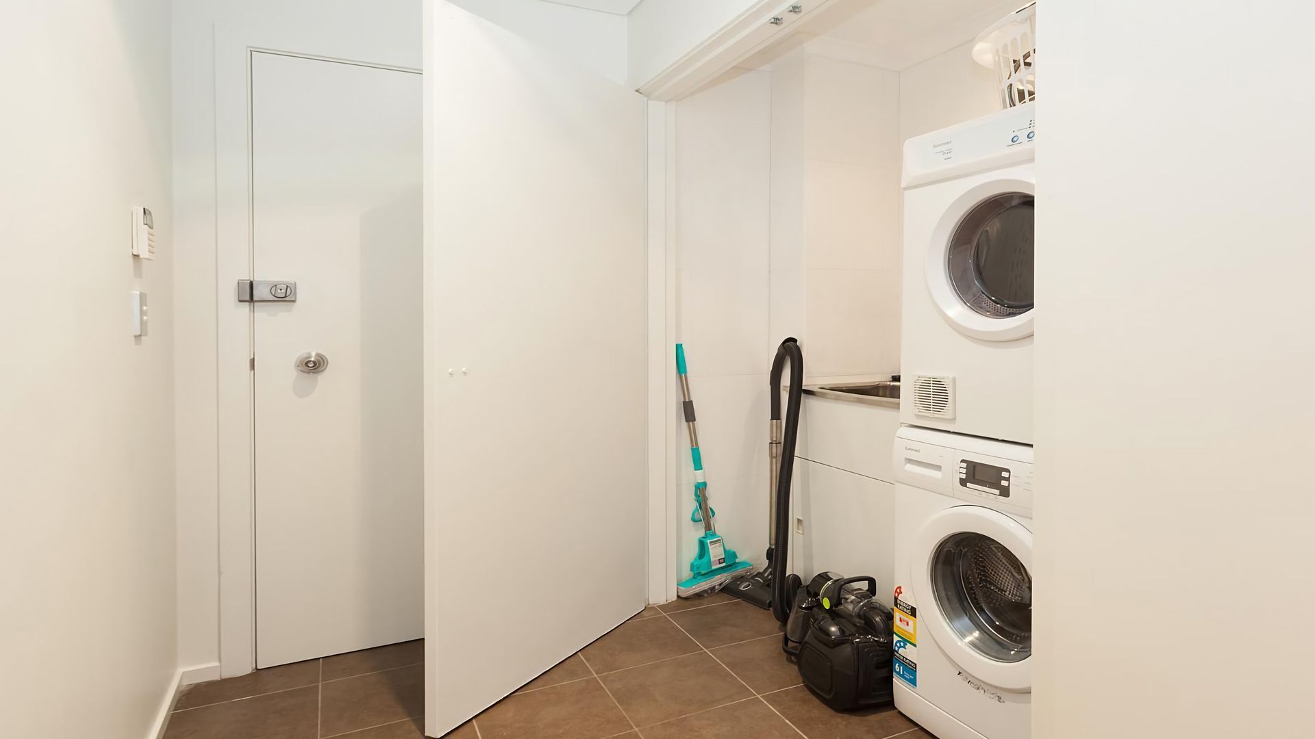 Une buanderie équipée d’un lave-linge, d’un sèche-linge et d’un aspirateur.