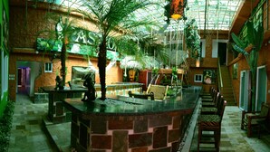 A spacious atrium with a high ceiling, stone walls, and a central seating area with chairs and tables.