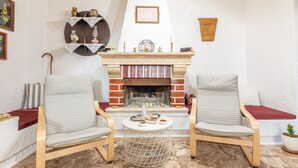 Un salon chaleureux avec deux fauteuils gris à revêtement en tissu, une petite table ronde, une cheminée en briques et un mur blanc à la texture intéressante.