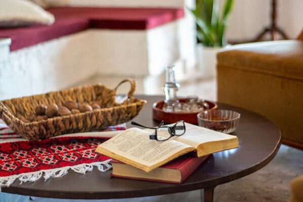 Un rincón acogedor para leer, con una mesa redonda, una cesta de aperitivos, un libro y un par de gafas.