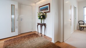 A hallway with a wooden floor, a brown shag rug, a small wooden table with a vase of flowers, and a framed picture on the wall. - Awesome 180° View 5*s
Central Location AVAILABLE NOV 15!










 (Albany)