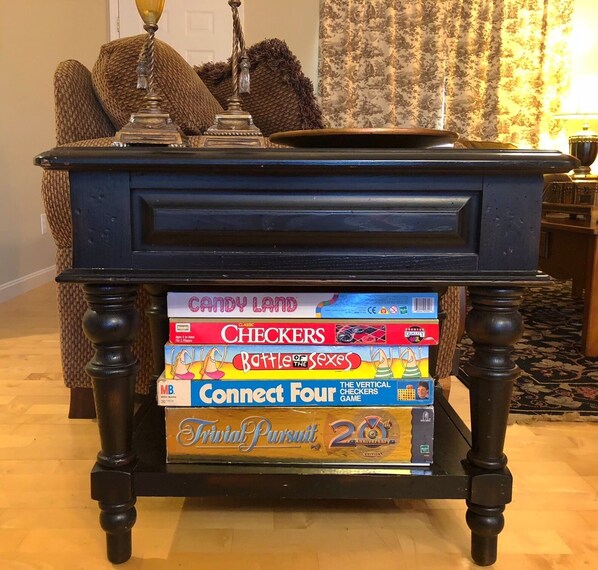 Una mesa de madera con acabado oscuro y cuatro patas, cubierta con una pila de juegos de mesa.