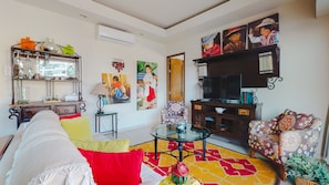 Uma sala de estar com sofá, mesa de centro, televisão e estante.