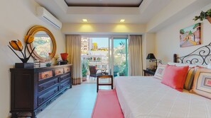 A hotel bedroom with a large bed, a dresser, a mirror, and a balcony with a view of the city.