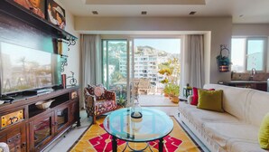 A modern living room with a sofa, a glass coffee table, and a TV on a wooden cabinet. - Charming Condo in V177! 1BD Condo for rent in Old Town, Puerto vallarta (Puerto Vallarta)