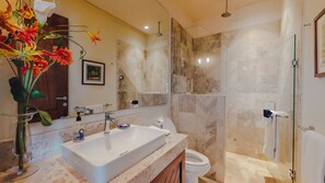 A modern bathroom with a large sink, mirror, and shower area.