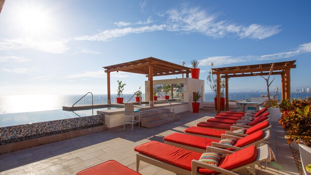 A rooftop pool area with lounge chairs, a small bar, and potted plants. - Charming Condo in V177! 1BD Condo for rent in Old Town, Puerto vallarta (Puerto Vallarta)