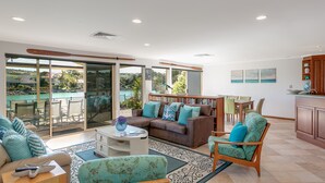 A spacious living area with a sliding glass door leading to a balcony, a dining area, and a kitchen. - Seas the Day - Lakefront getaway by the beach (Encounter Bay)