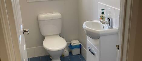 A small bathroom with a toilet, sink, and a window with blinds.