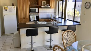 Una cocina moderna con una isla central, taburetes de bar y una mesa de comedor.