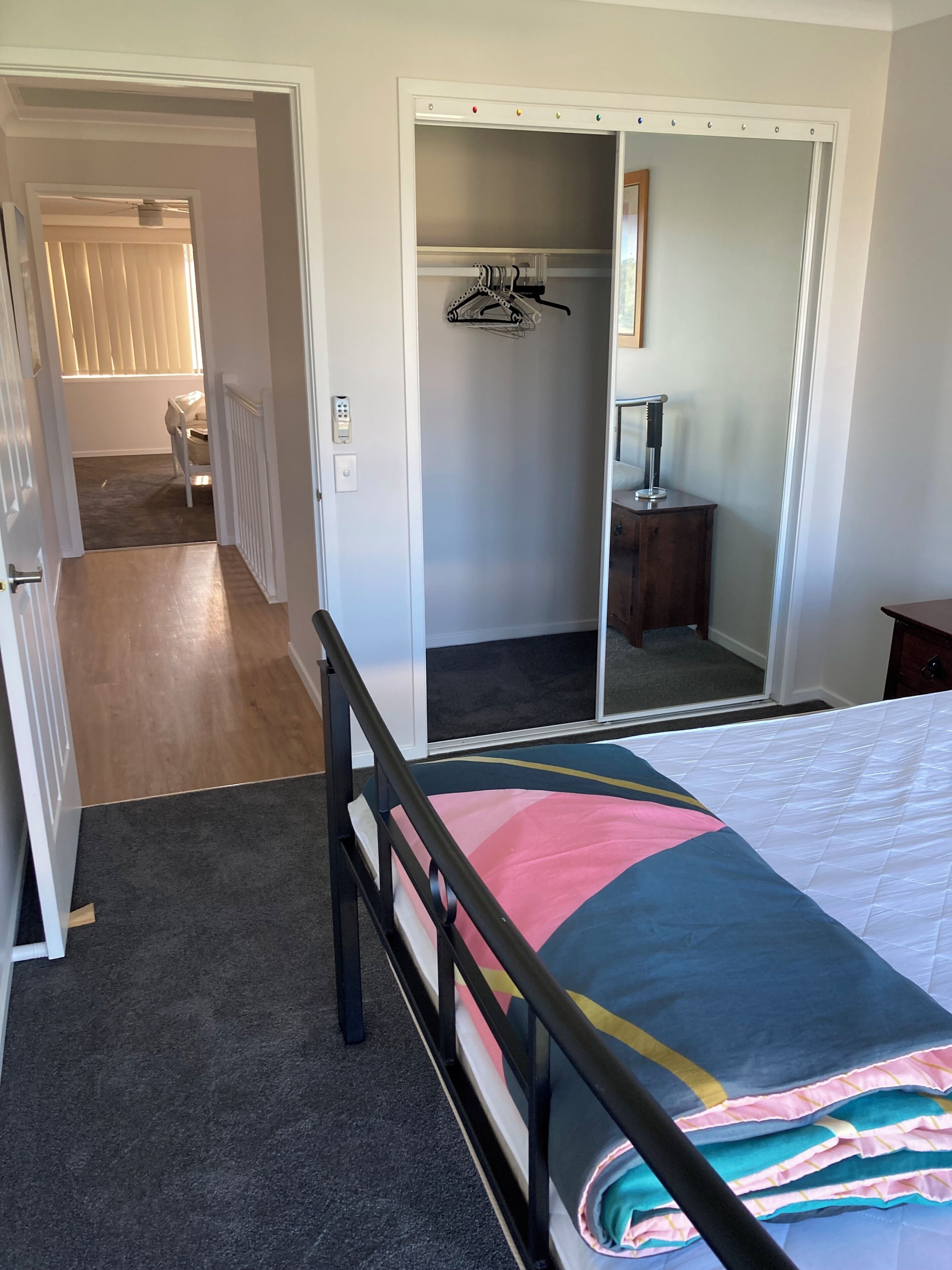Une chambre à coucher comprenant un lit, une armoire, un miroir et une porte donnant sur une autre pièce.