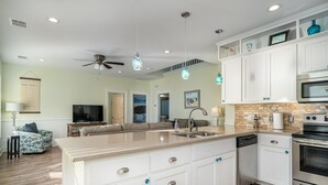 Una cocina moderna con armarios blancos, una isla grande con pileta y electrodomésticos de acero inoxidable.