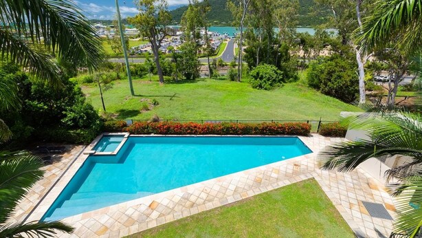 A swimming pool with a clear view of a road and buildings in the background. - Le Jarden Vue Du Port - Airlie  Beach (Airlie Beach)
