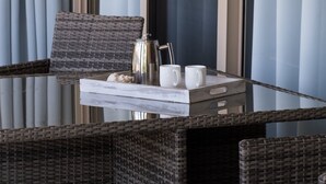A wicker chair and table set up near a window with curtains, a coffee pot, and two white mugs. - Le Jarden Vue Du Port - Airlie  Beach (Airlie Beach)