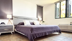 Un dormitorio moderno con cama, mesitas de noche, lámparas y ventana con vistas.