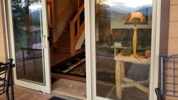 A home interior with a wooden staircase, a dining area with chairs, and a living room with a sofa and a lamp. -  RIDGEVIEW RETREAT/ Huge views! Hot tub, fireplaces, A/C,  and location! (Estes Park)