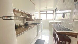 A kitchen with white cabinets, a stainless steel sink, and a wooden countertop. - Fully furnished apartment with 3 bedrooms and 2 parking spaces. (Prainha)