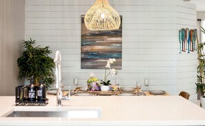 Una cucina moderna con zona pranzo, caratterizzata da una lampada a sospensione, un quadro e una pianta.