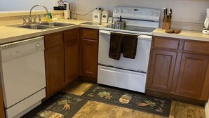 Una cocina con armarios de madera, un microondas, una estufa y un lavavajillas.
