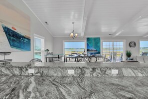 A modern kitchen with marble countertops, a dining area with a view, and a ceiling with a chandelier.