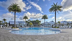 A swimming pool with lounge chairs and palm trees, surrounded by houses.