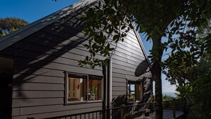 A modern house with a sloped roof, a wooden deck, and a view of the ocean. - 4 Wheel Drive included. 5-minute walk from Ferry to car.
Hot on arrival Spa Pool (Onetangi)