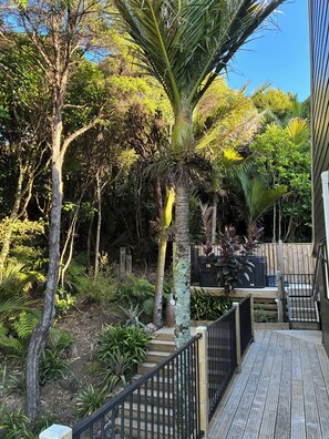 A wooden deck with a metal railing, surrounded by lush greenery and trees.