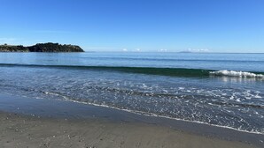 A beach with clear blue water, gentle waves, and a distant island.