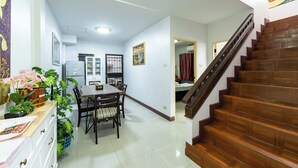 A spacious dining area with a wooden table and chairs, a refrigerator, and a staircase leading to an upper floor. - Large 3 Bedroom House Near Old City and Night Bazaar  (Tambon Hai Ya)