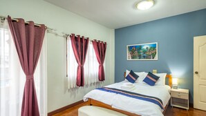 A bedroom with a bed, bedside table, and a painting on the wall. - Large 3 Bedroom House Near Old City and Night Bazaar  (Tambon Hai Ya)