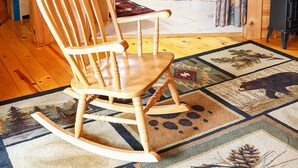 A wooden cabin interior with a rocking chair, a wooden table, a bathtub, and a patterned rug. -  Branson MO Log Cabin Private Porch Quiet Mtn. Forest View Above Lake, Handicap  (Blue Eye)