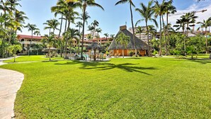 A tropical resort with a thatched-roof hut, palm trees, and a pool area. - Marina Sol Los Cabos Haven - Walk to Medano Beach! (Cabo San Lucas)