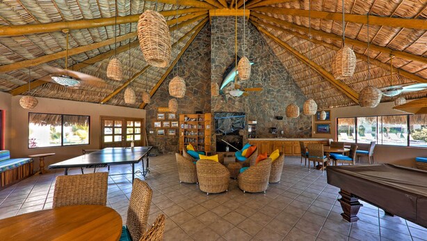 A spacious lounge area with a pool table, comfortable seating, and a stone wall backdrop. - Marina Sol Los Cabos Haven - Walk to Medano Beach! (Cabo San Lucas)
