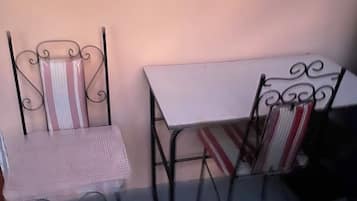 A small outdoor seating area with two metal chairs and a table, against a plain wall.