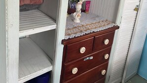 Un armario con varias repisas, un espejo y un cajón de cómoda con encaje.