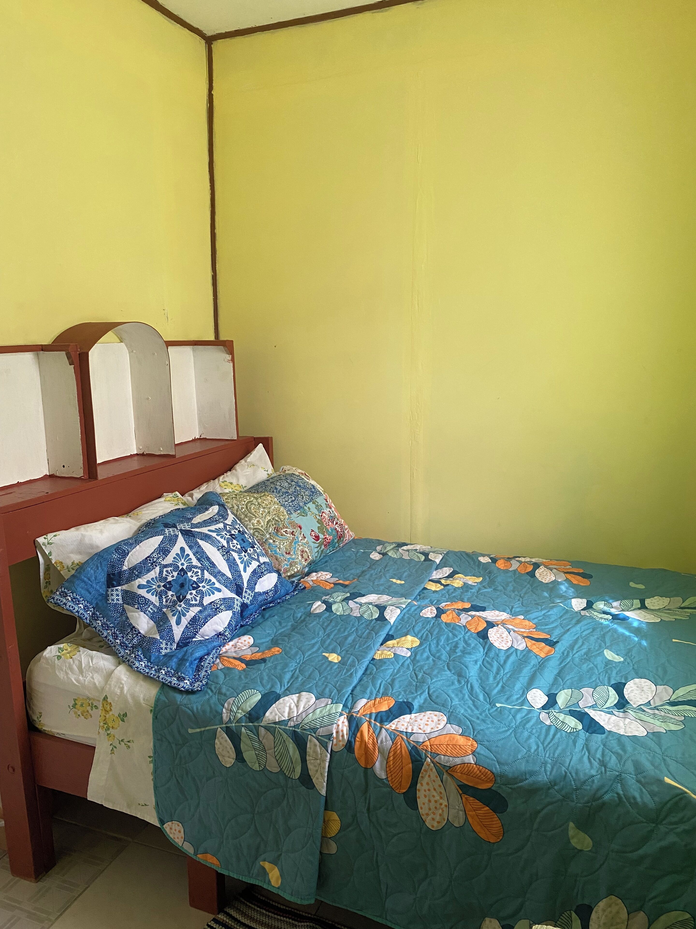 A single bed with a floral-patterned quilt and a headboard with a curved design.