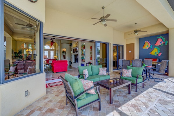 A spacious living area with a green sofa set, a wooden coffee table, and a ceiling fan.