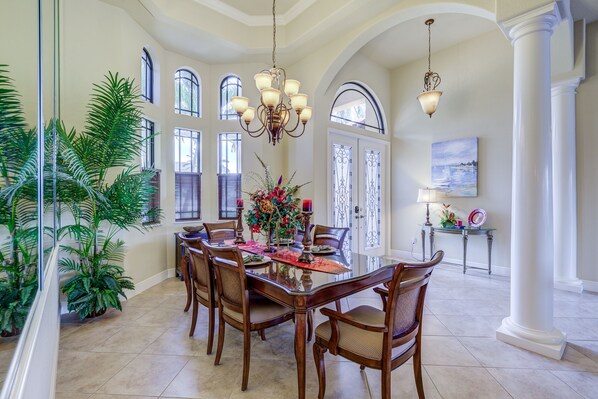 Enjoy meals in this dining area with a large table and six chairs, surrounded by natural light and greenery.