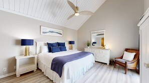 A bedroom with a bed, nightstands, a dresser, a chair, a ceiling fan, and a mirror.
