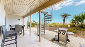 An outdoor patio with a spiral staircase, a grill, and seating area.