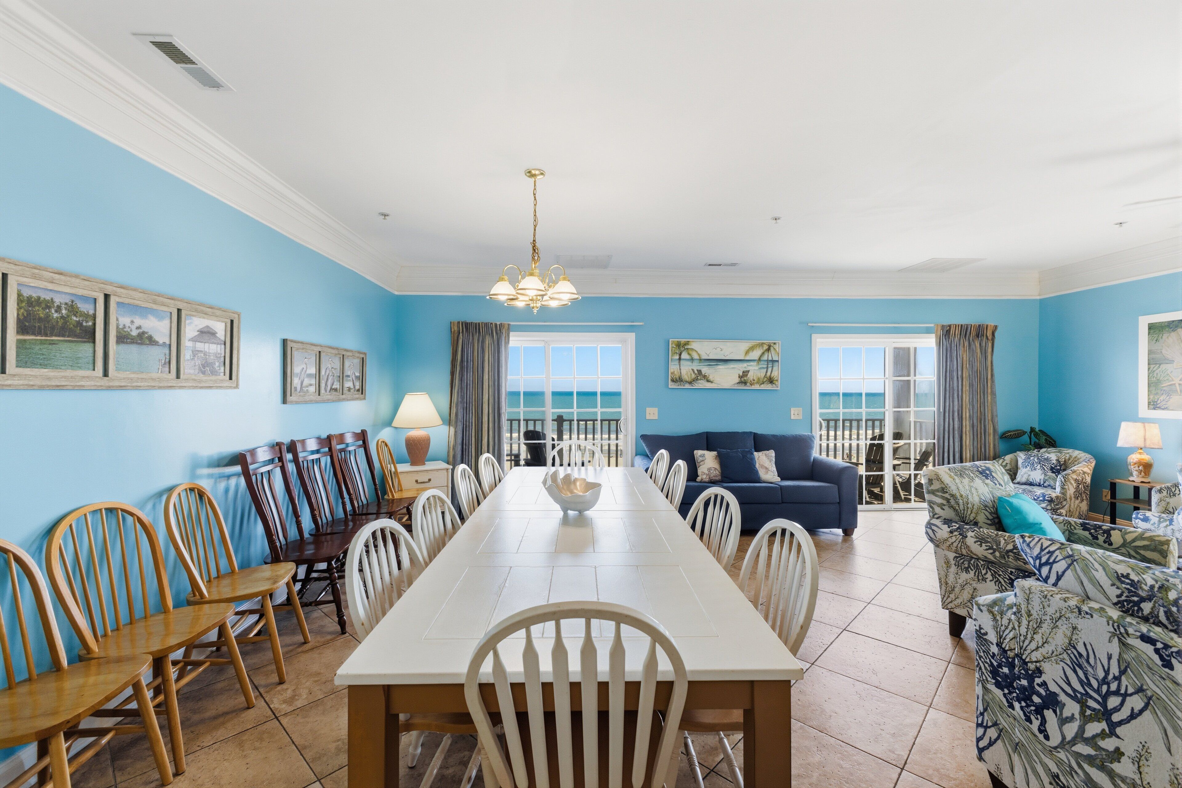 A dining area with a long table, chairs, and a chandelier.