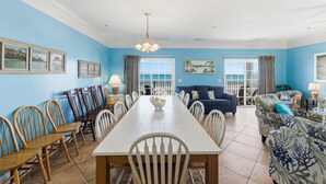 A dining area with a long table, chairs, and a chandelier.