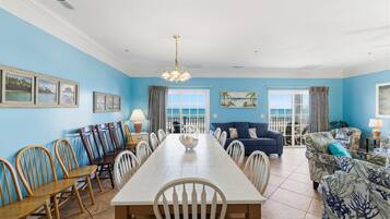 A dining area with a long table, chairs, and a chandelier.